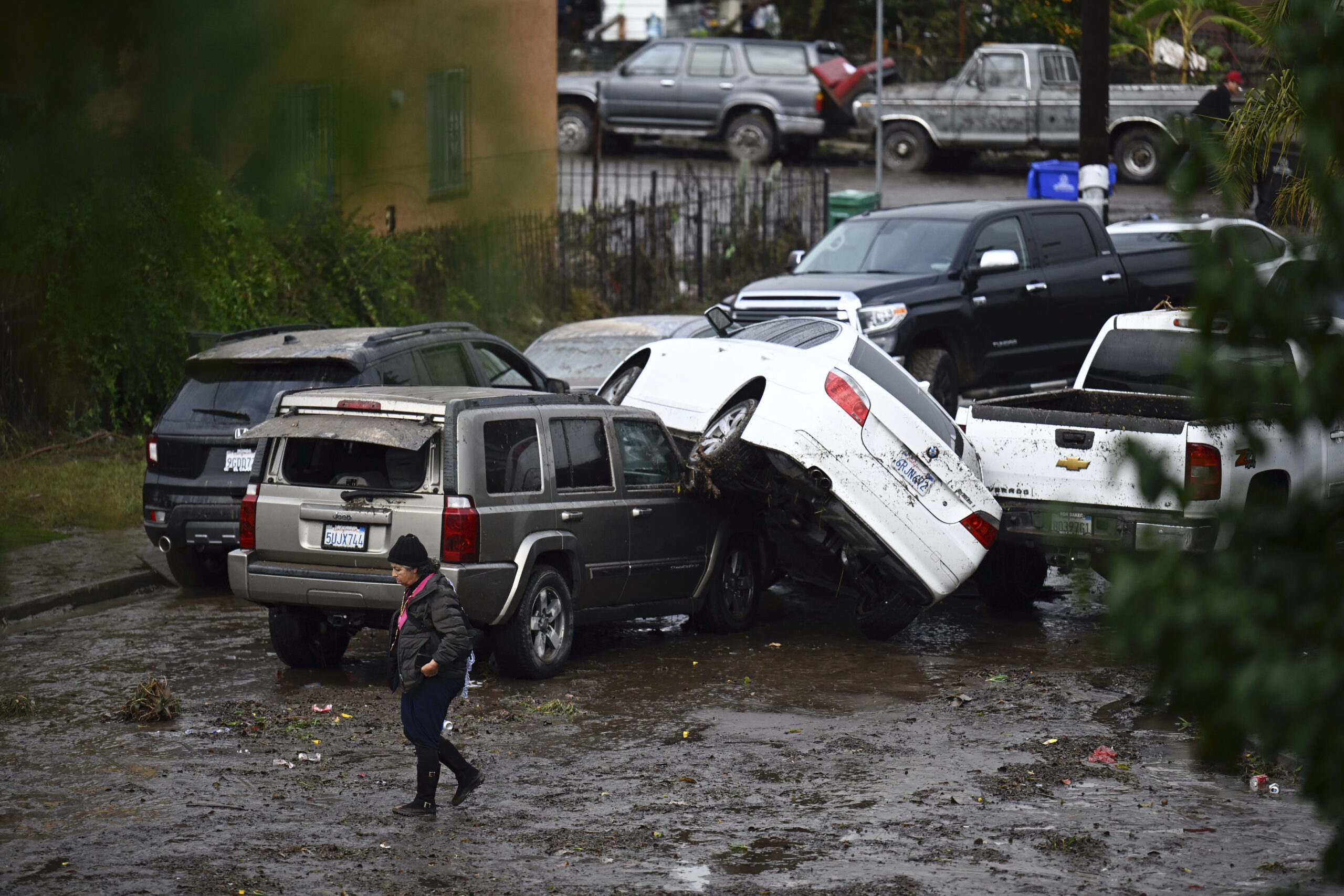 A woman walks by cars damaged by floods during a rainstorm in San Diego on Monday, Jan. 22, 2024. (...