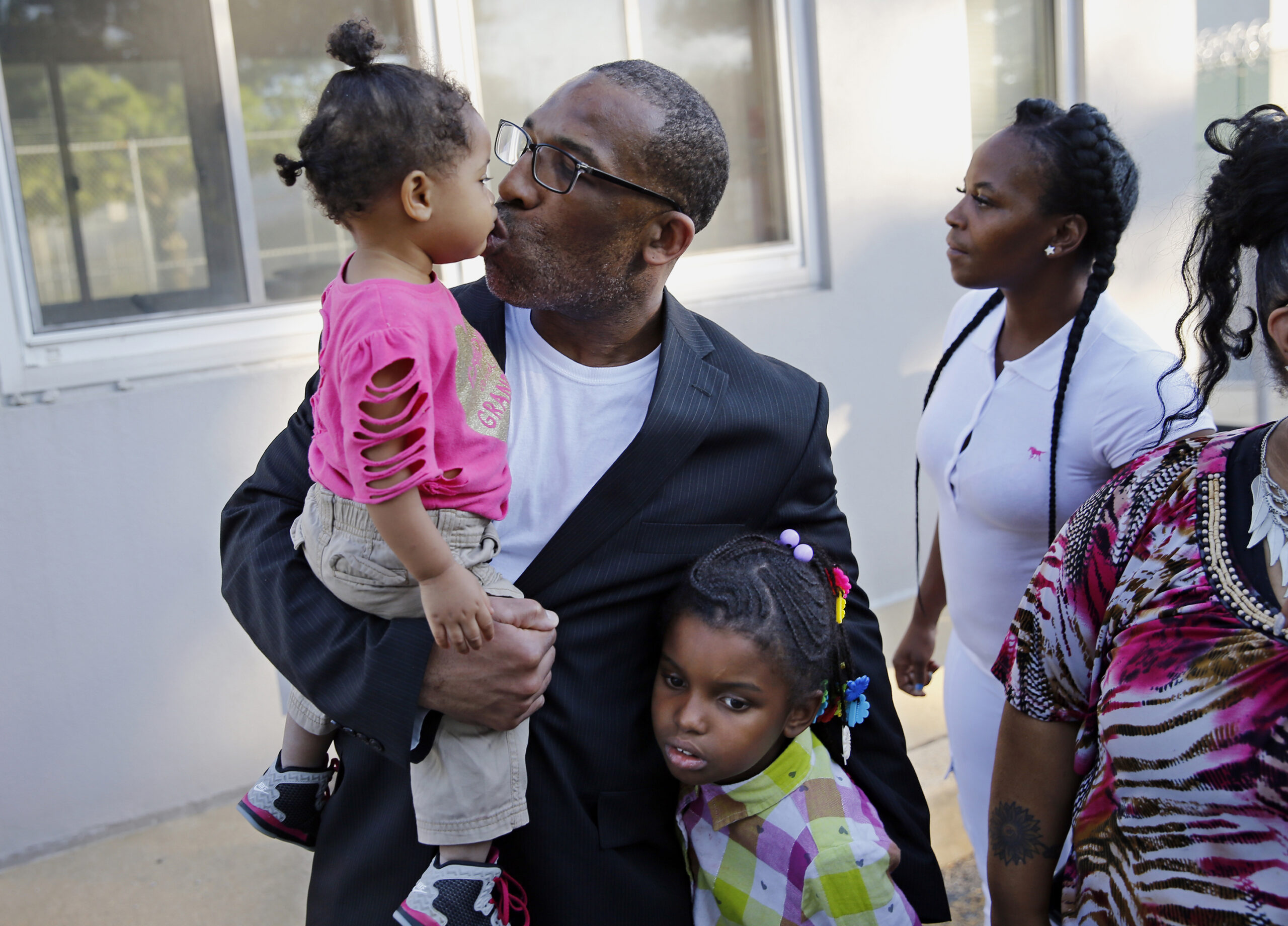 FILE - Anthony Wright gets a kiss from his granddaughter Romera Wright, 1, and holds on tight to hi...