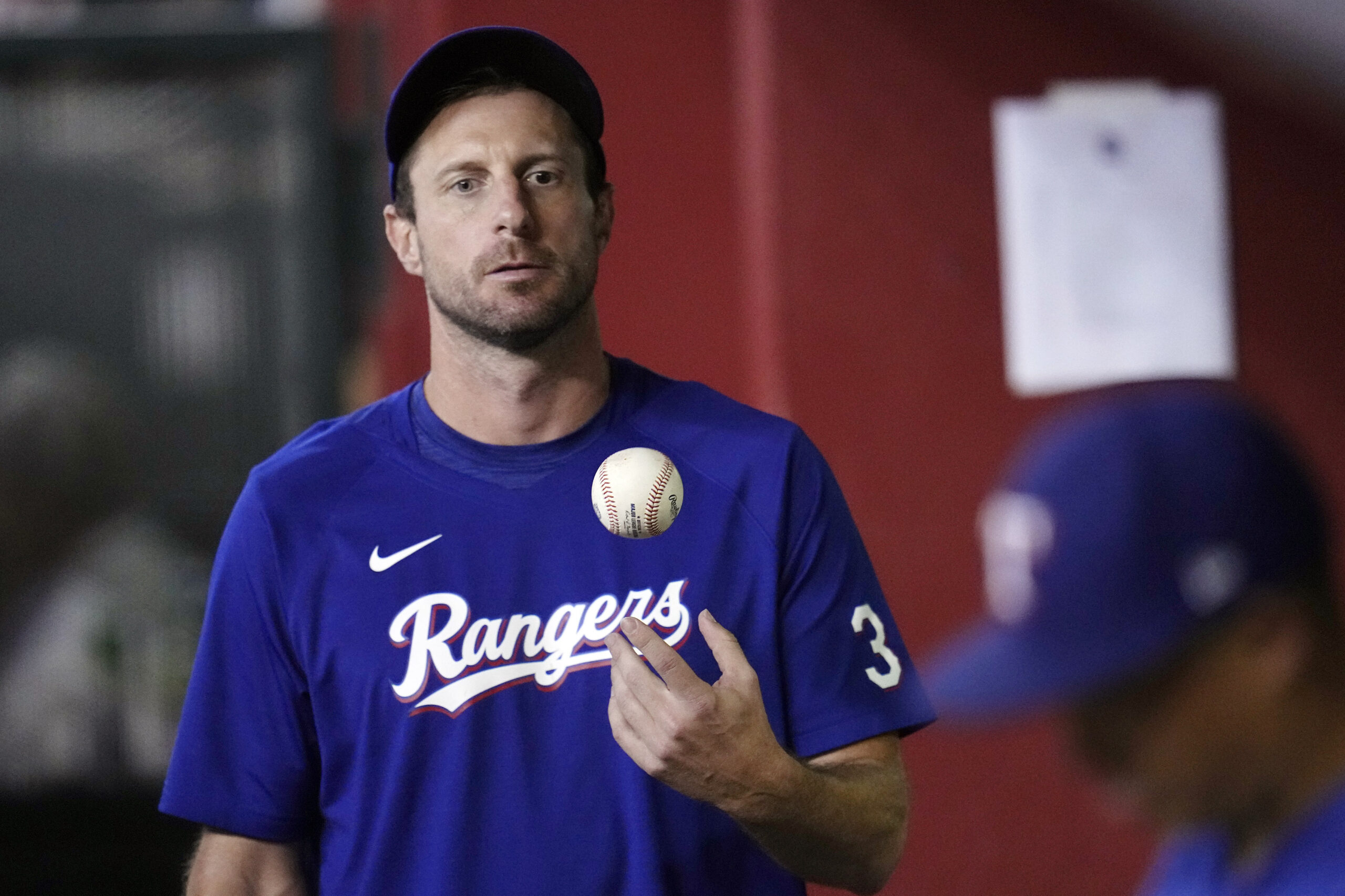 FILE- Texas Rangers' Max Scherzer flips the ball in the air as he paces the dugout during the seven...