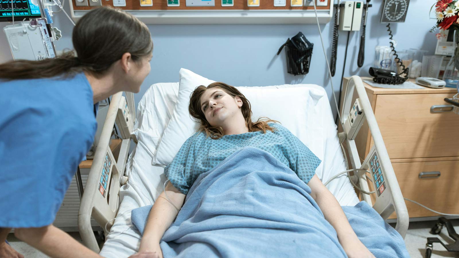 Stock image of a medical provider attending to a woman in a hospital bed....