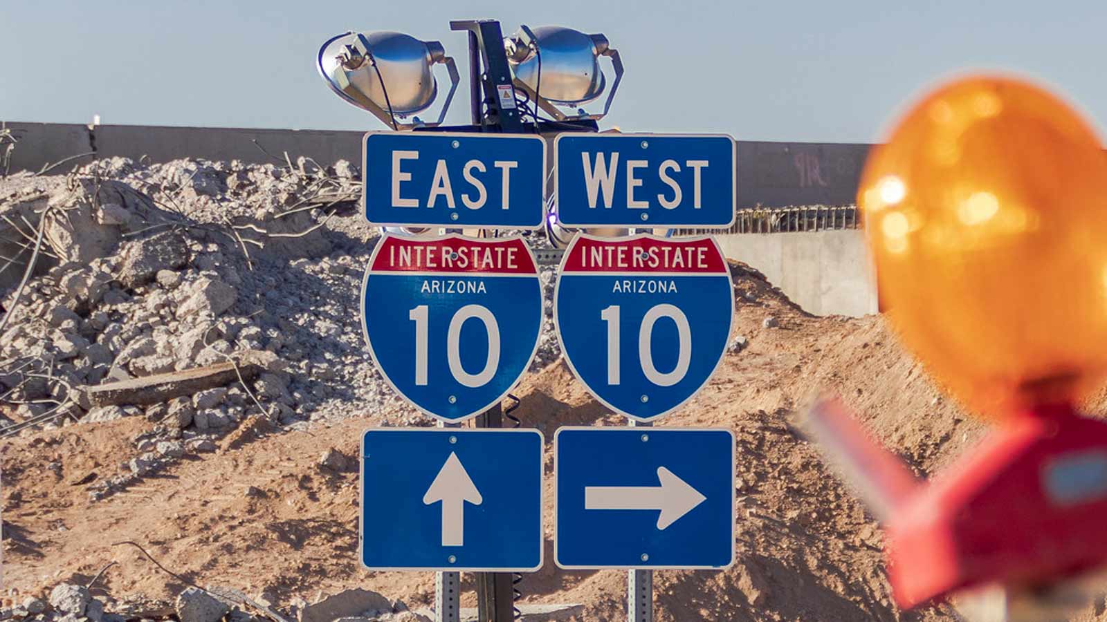 Freeway signs signify Interstate 10 in Phoenix, with the light from a traffic barrier visible to th...