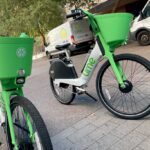 White Lime-branded e-bikes with green trim and baskets on a city street in Phoenix