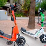 Two e-scooters, one from Spin and one from Lime, are seen parked in Phoenix, Arizona