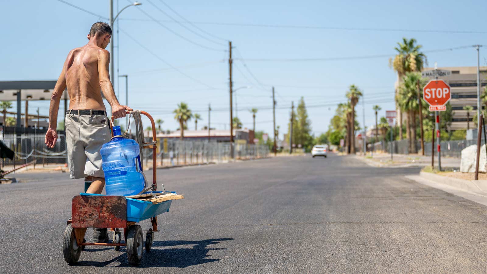 A shirtless man transports water jugs on July 14, 2023, in Phoenix, Arizona....