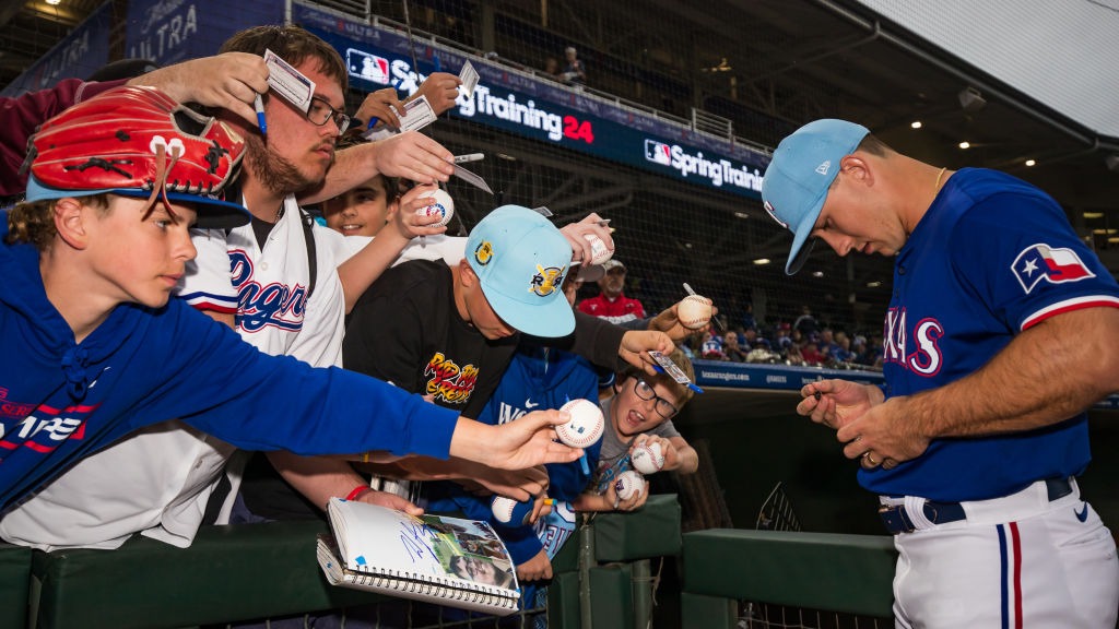 Wyatt Langford #82 of the Texas Rangers signs autographs before the Spring Training Game against th...