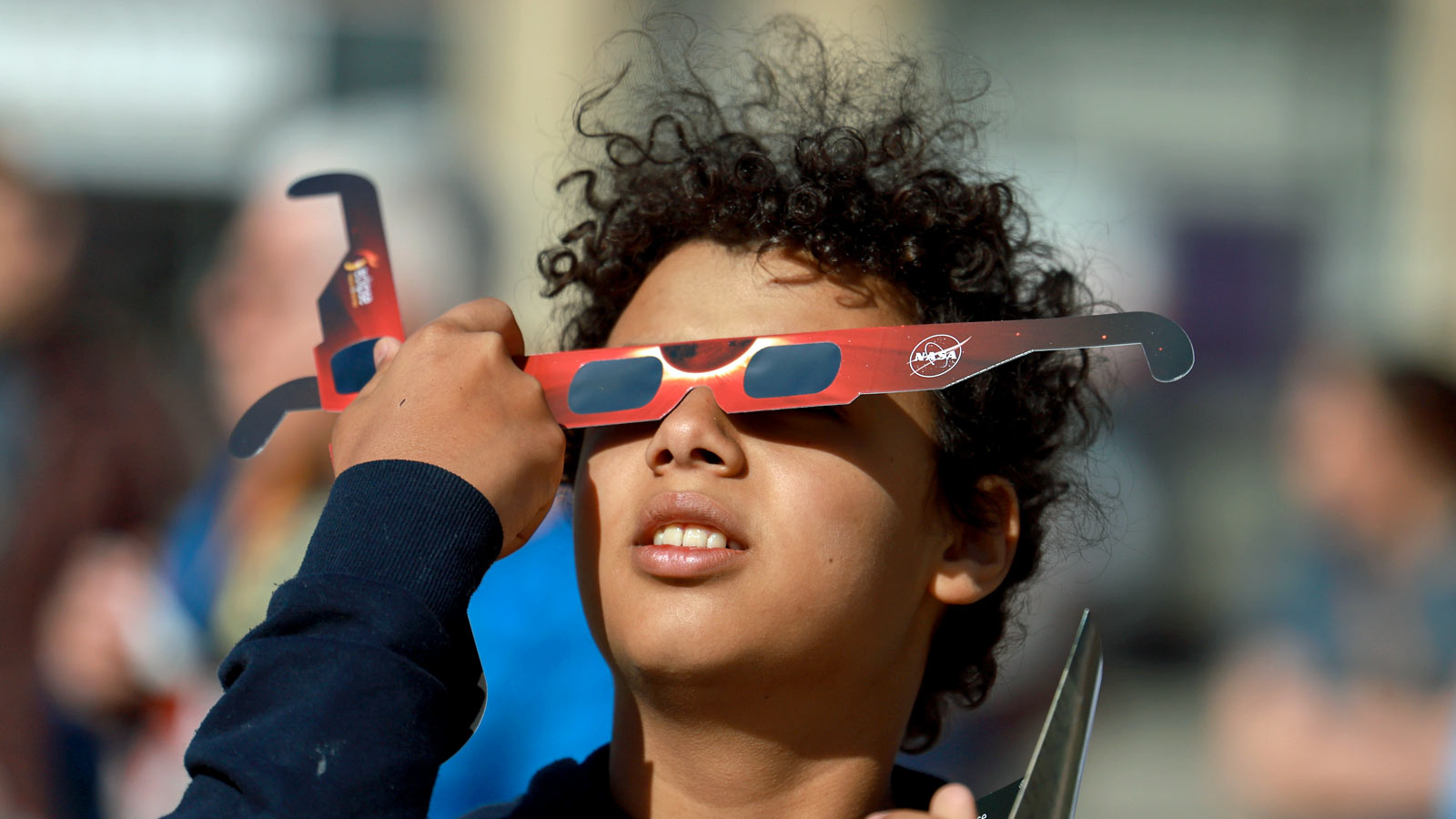 Junior Espejo looks through eclipse glasses being handed out by NASA on April 08, 2024, in Houlton,...