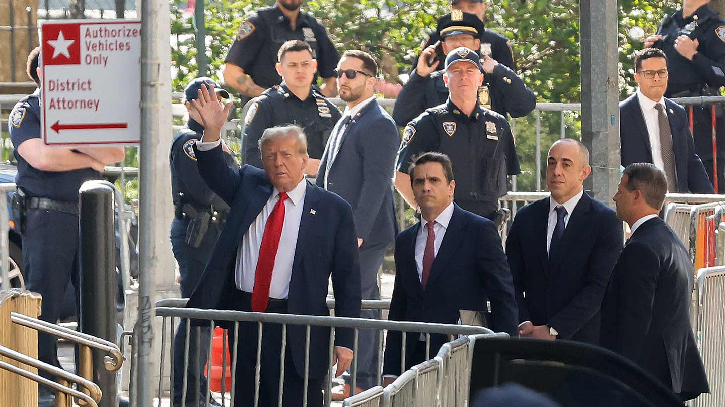 Former President Donald Trump waves as he arrives at Manhattan criminal court with his legal team on Monday, April 15, 2024.