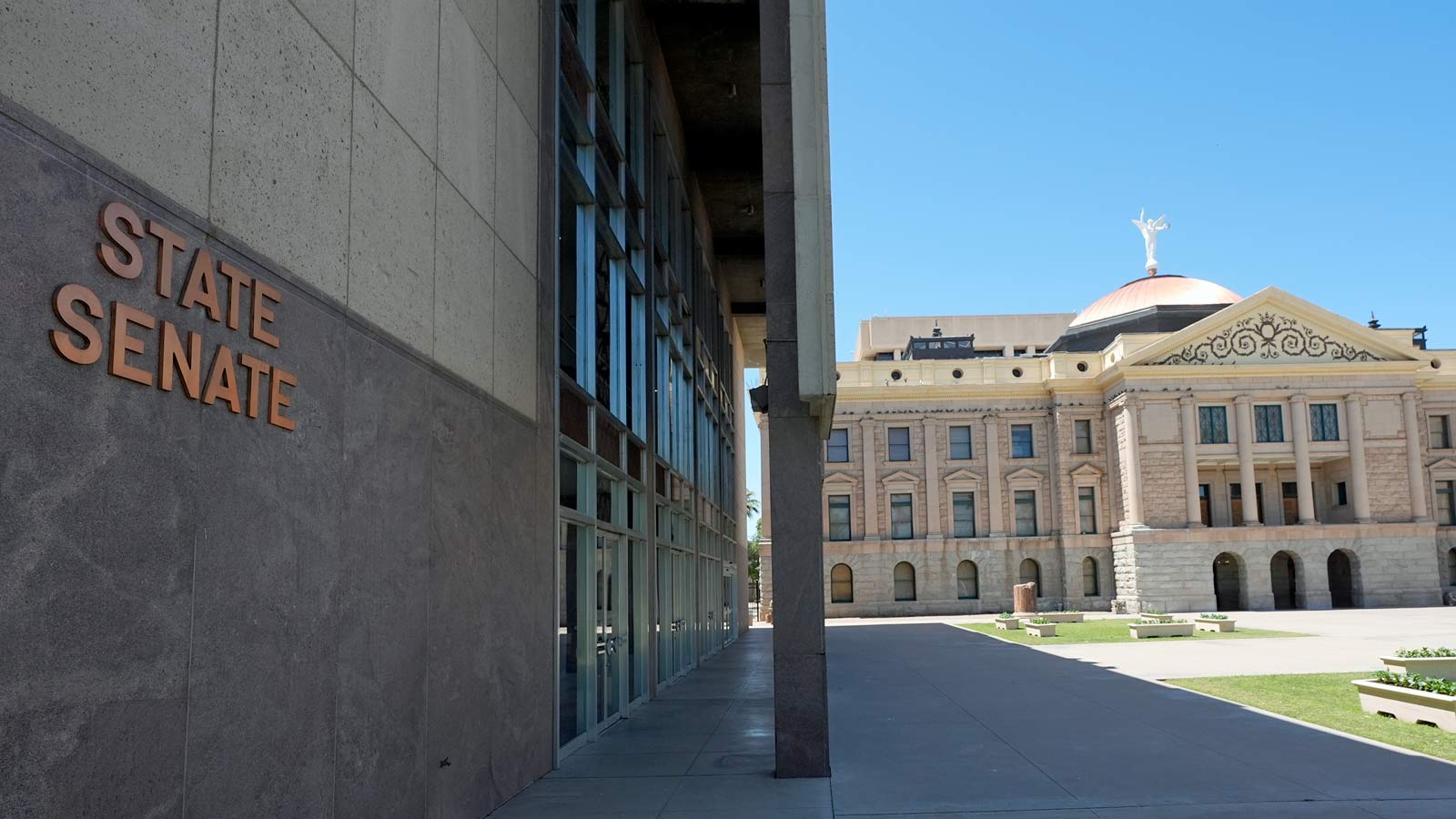 Exterior view of the Arizona Senate building the the copper dome of the state Capitol in the backgr...