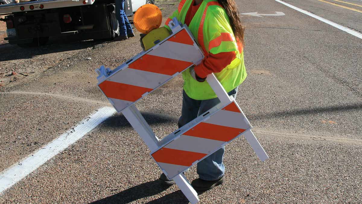 A road worker carriers an orange and white barricade. Closures are scheduled this weekend on Inters...