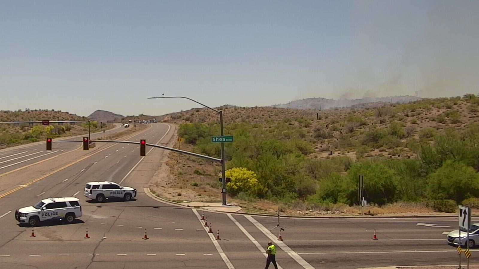 Police are seen implementing a closure on State Route 87 at Shea Boulevard with smoke from a brush ...