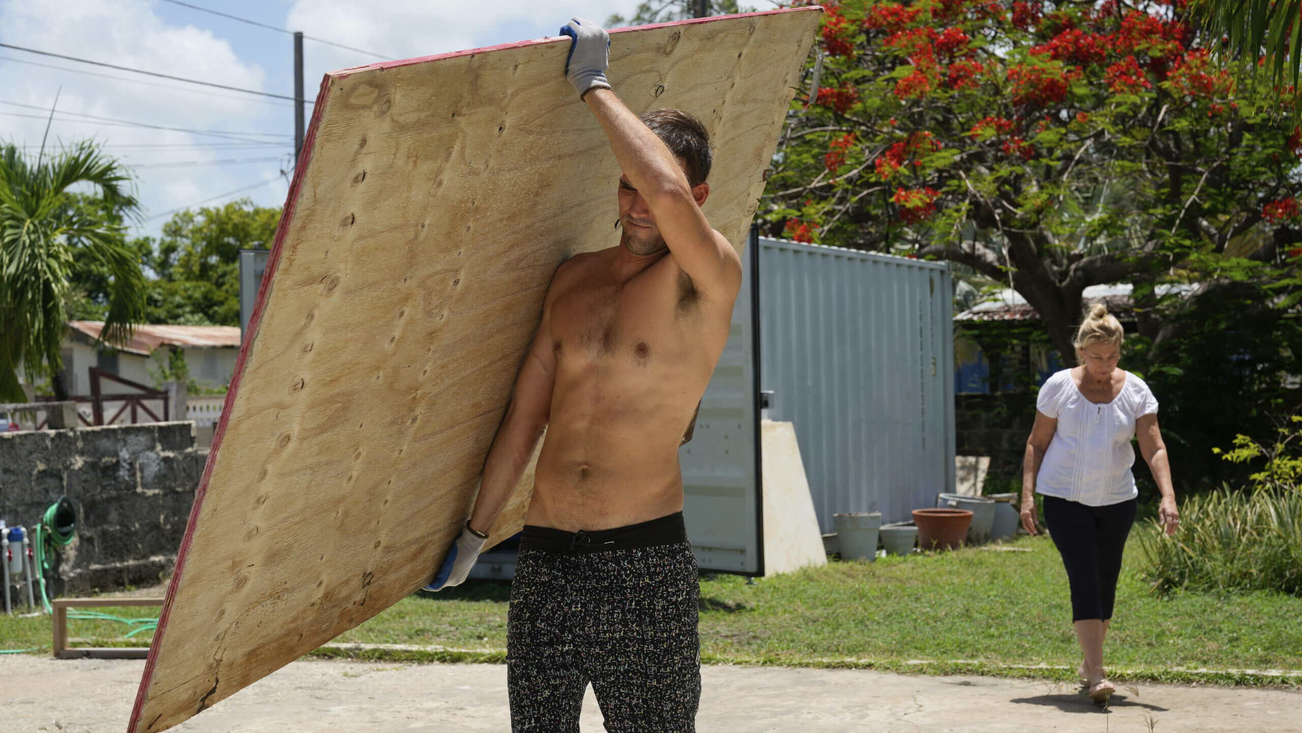 A resident carries wood to cover his house's windows in preparation for Hurricane Beryl, in Bridget...