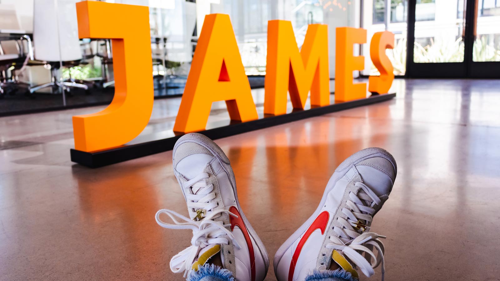 Promotional photo from The James Agency showing a person's sneaker-clad feet kicked up in the lobby...