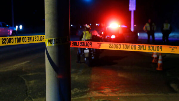 Police lights in the distance at night while yellow crime tape is in foreground....