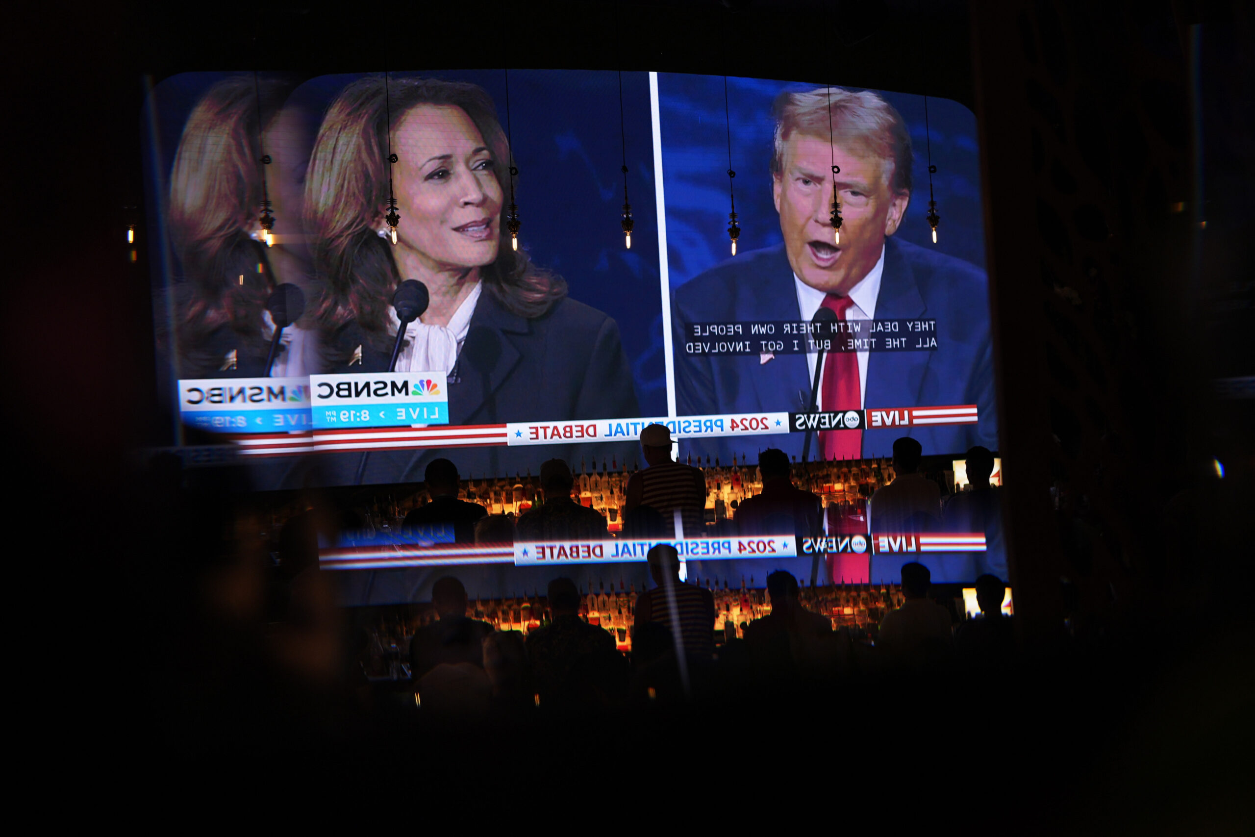 Reflected in a mirror, people watch the presidential debate between Republican presidential nominee...