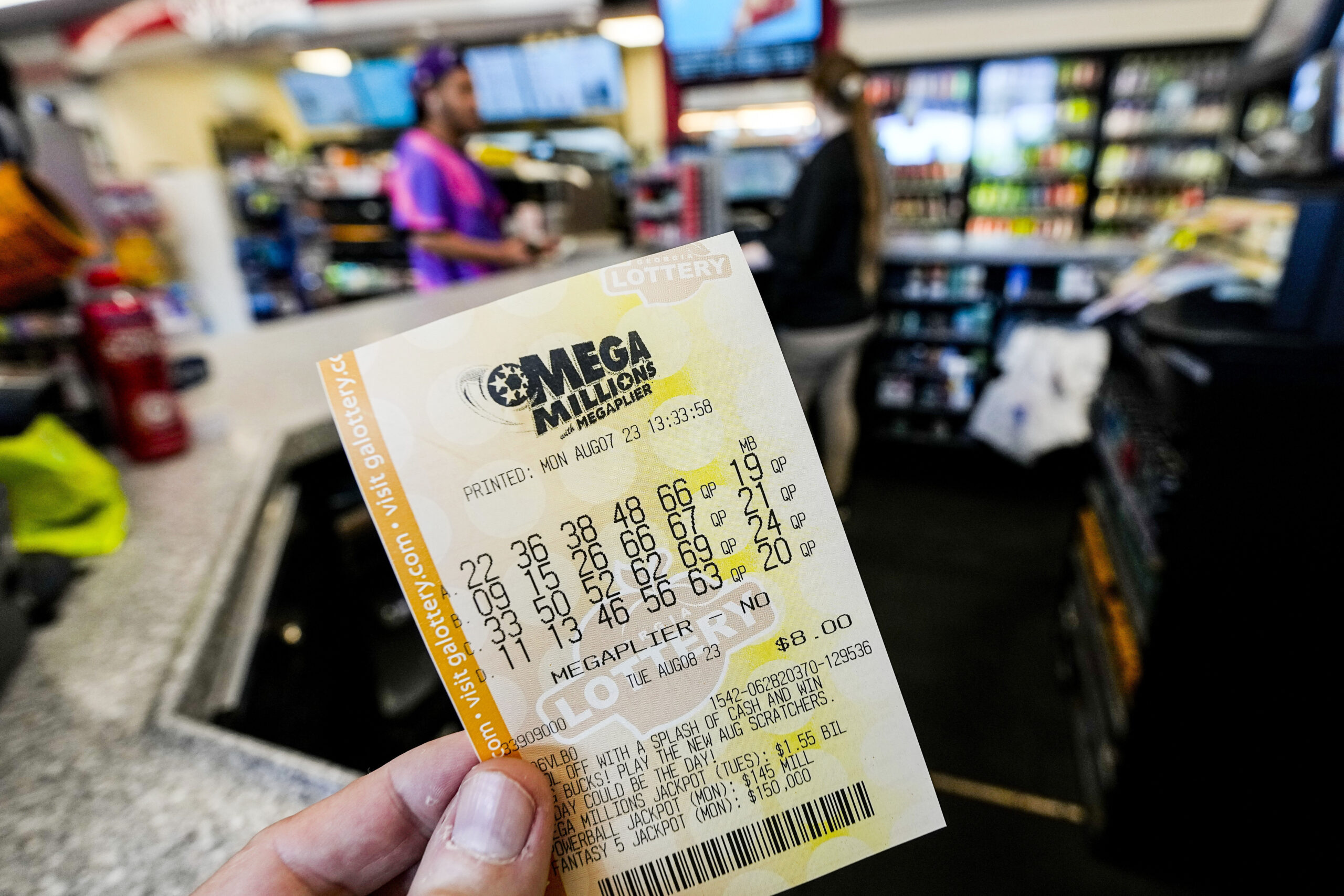 FILE - A Mega Millions ticket is seen as a person makes a purchase inside a convenience store, Aug....