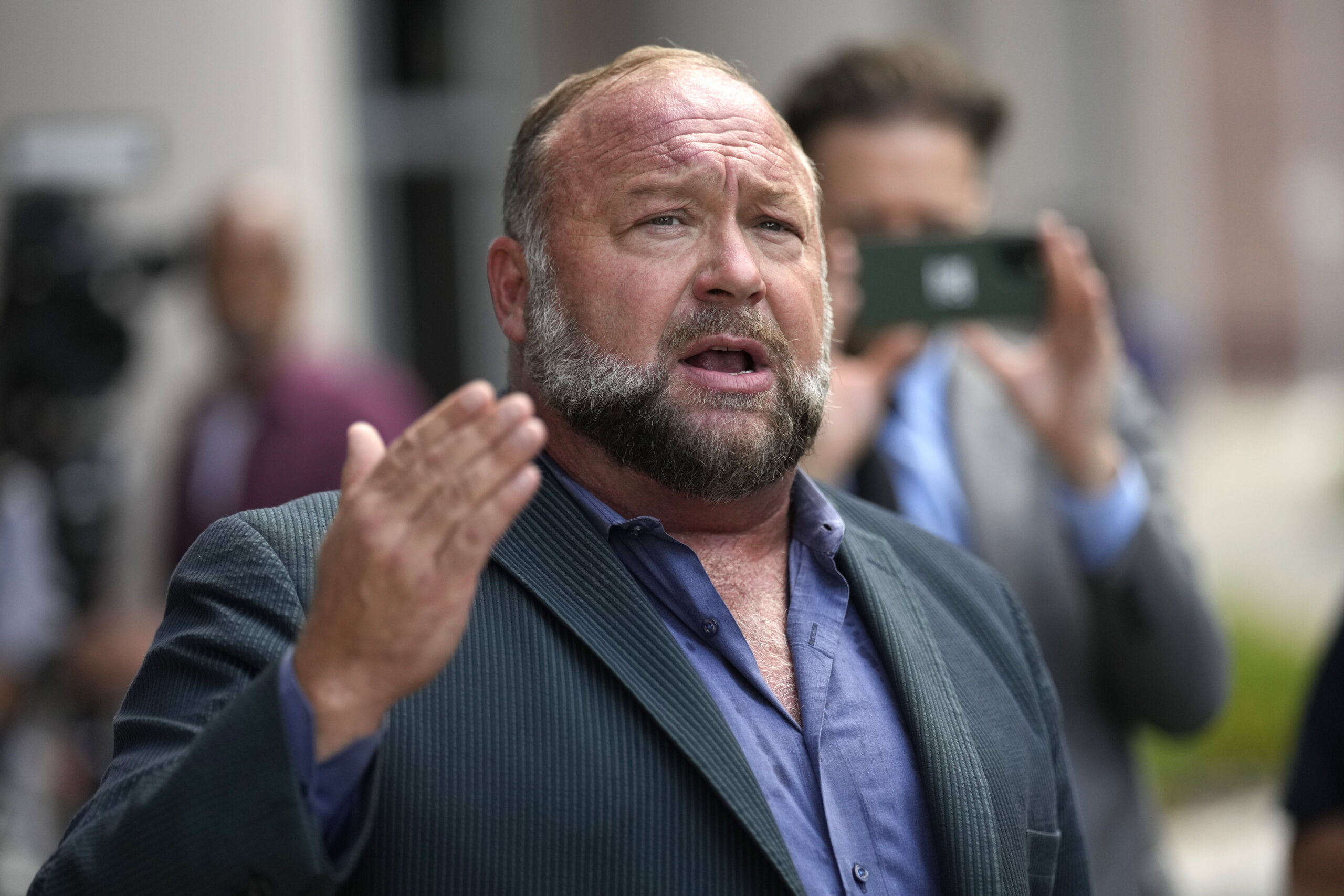 FILE - Alex Jones speaks to the media after arriving at the federal courthouse for a hearing in fro...