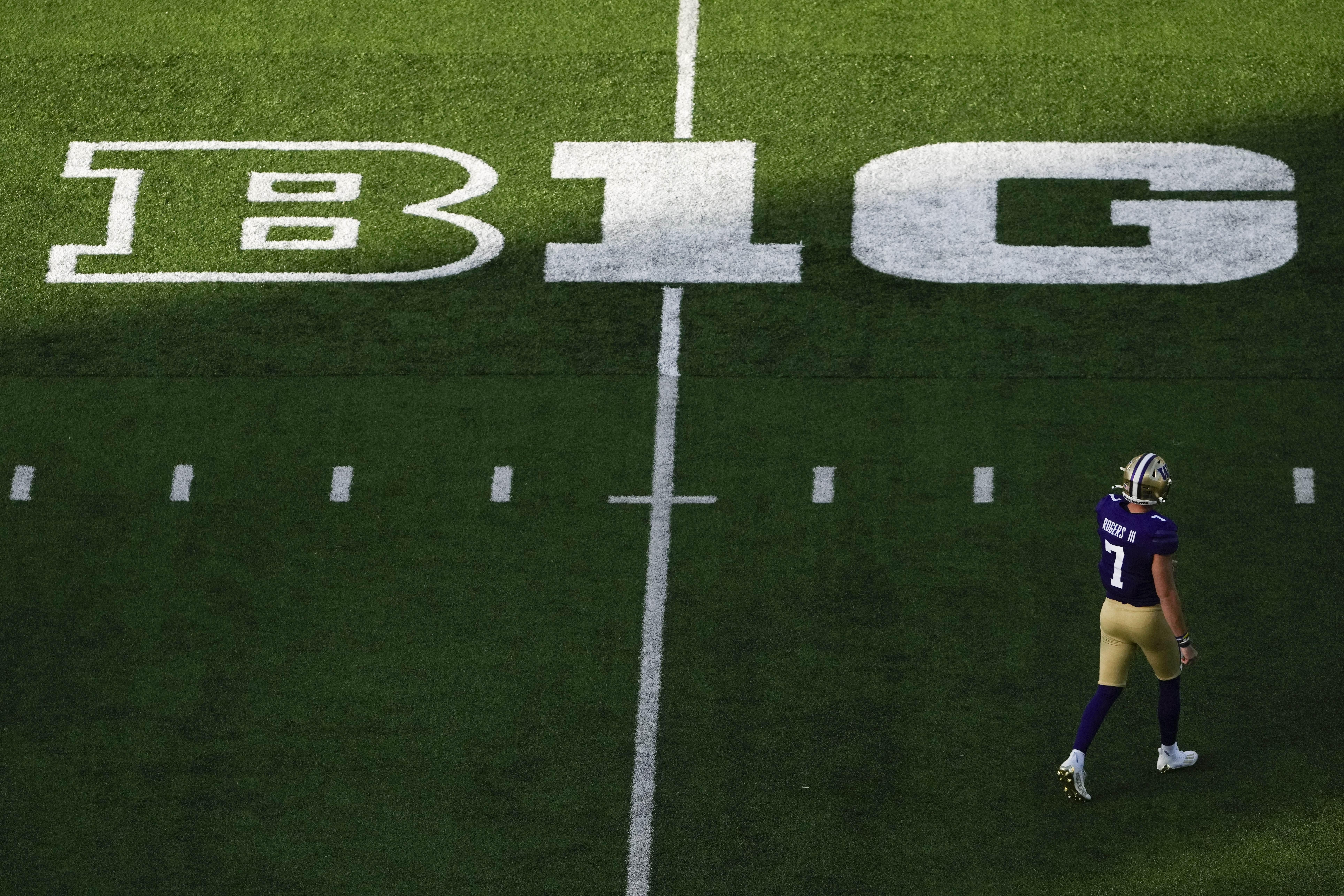 Washington quarterback Will Rogers walks on the field near a Big Ten logo during the first half of ...