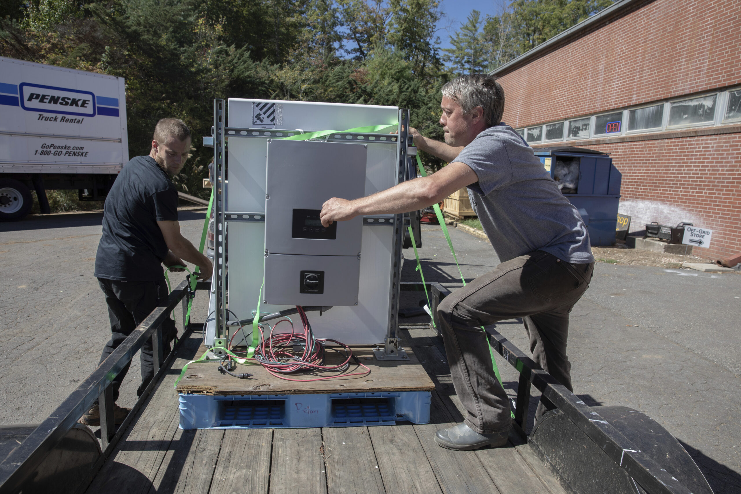 Henry Kovacs, left, and Hayden Wilson, right, volunteers with the Footprint Project, load two Tesla...