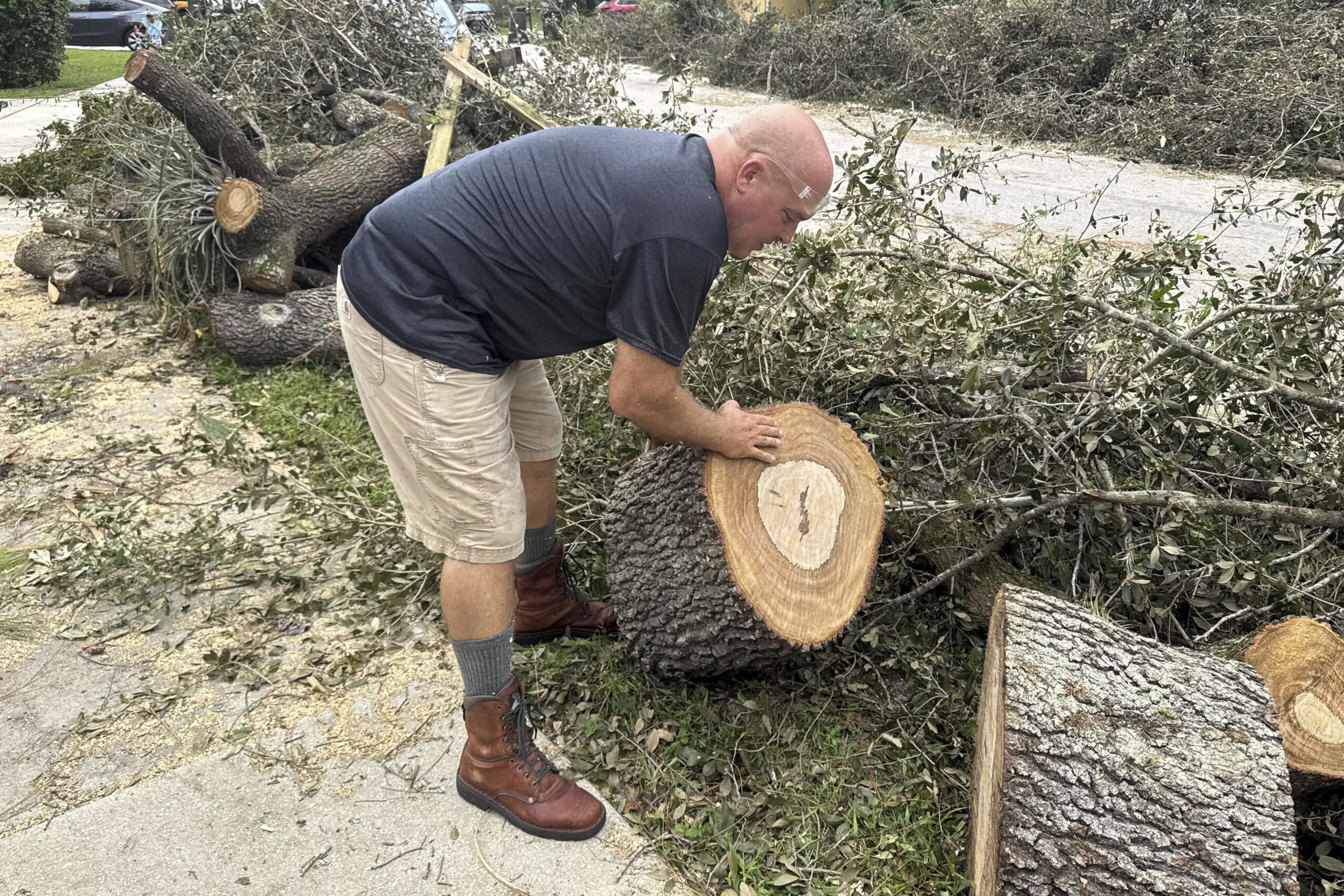 Tony Brazzale removes part of a tree felled by a tornado from in front of his house in Wellington, ...