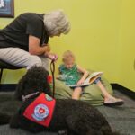 Therapy dog Maire listens to kids read during the Sit, Stay, read program. (Shira Tanzer/KTAR News)
