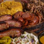 Caldwell County BBQ Peoria platter piled high with slow-smoked brisket, pulled pork and all the fixins