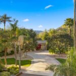 The estate features a full tennis court positioned among the expansive lawns, offering both recreation and a striking visual anchor to the outdoor layout.