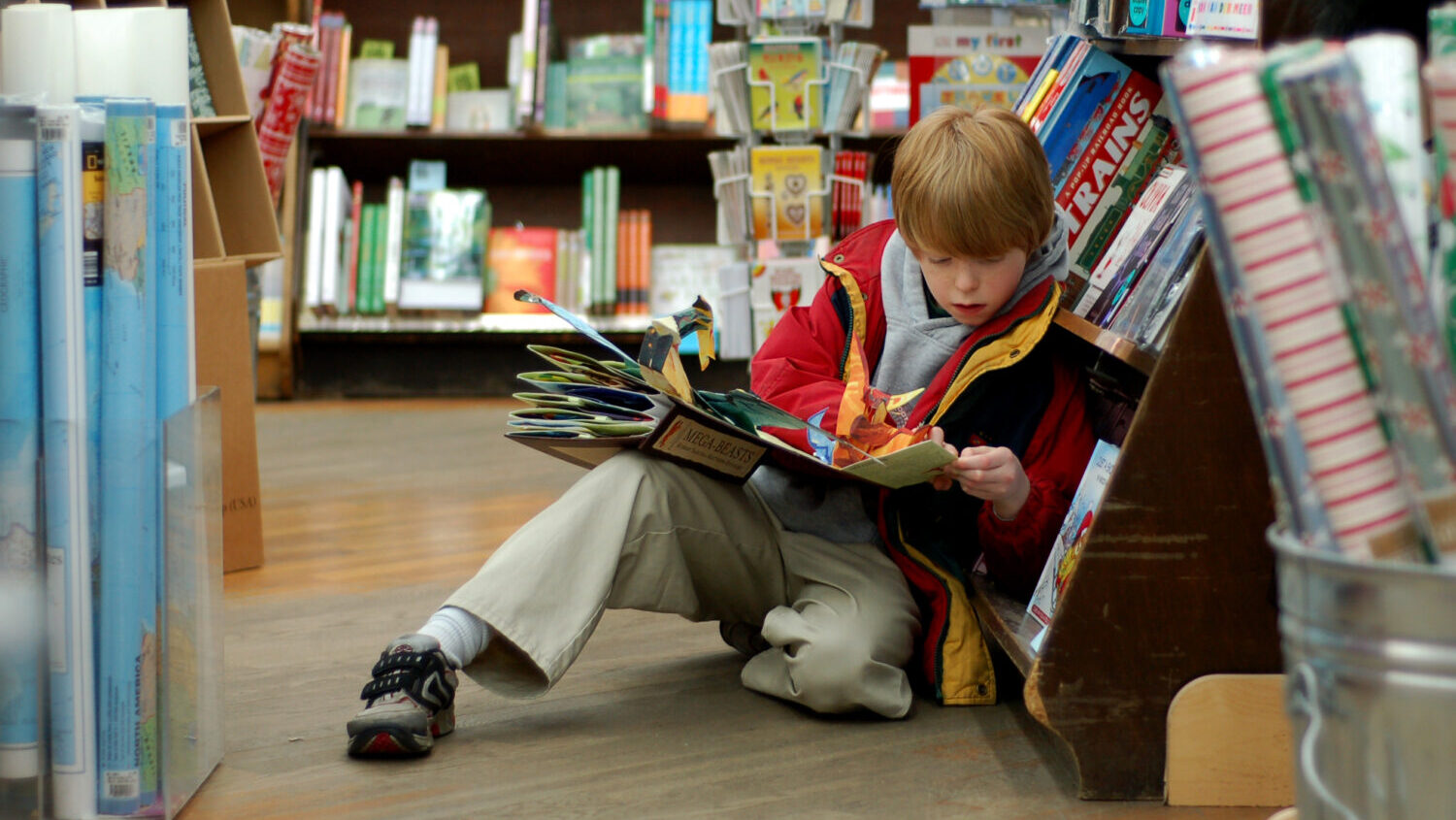 A child reading in Brookline Booksmith, an independent bookstore. (WikiCommons)...