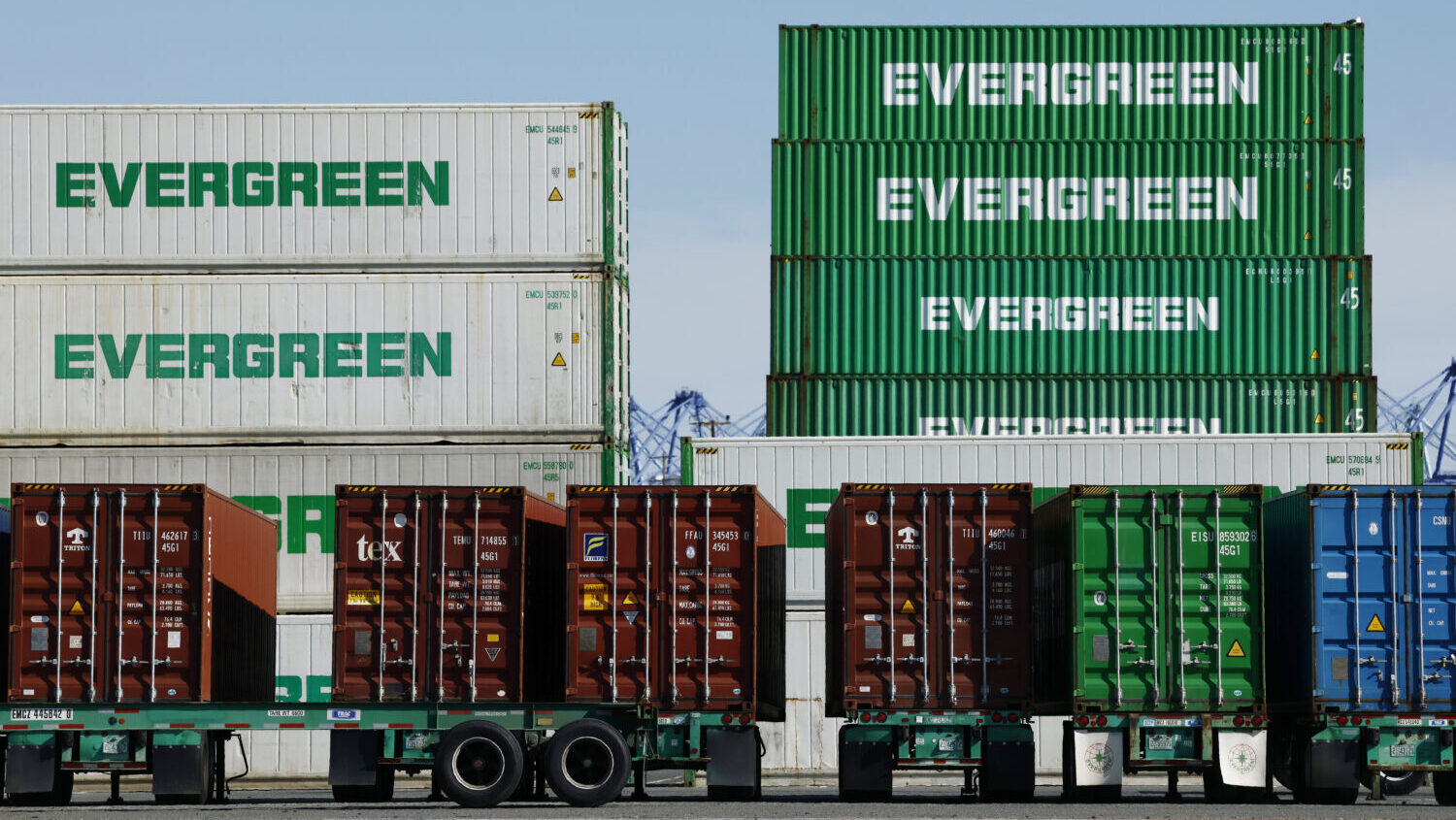 Shipping containers stand stacked while others rest on truck transport chassis at the Port of Los A...