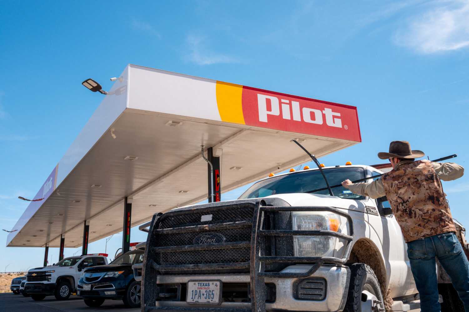 ODESSA, TEXAS - MARCH 17: A driver cleans his windeshield while pumping gas at a Pilot Travel Cente...
