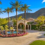 The exterior showcases a series of soaring arches and elegant architectural lines that complement the surrounding desert landscape and mountain backdrop.
