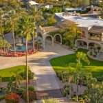 A grand electronic gate opens to a long curved driveway, creating a dramatic and secluded arrival experience that sets the tone for the entire property.