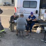 A Circle the City medical worker examines a patient outside the nonprofit's mobile unit at a Phoenix park. The city is considering an ordinance that would require permits for medical treatment in parks. (Credit: Balin Overstolz-McNair)