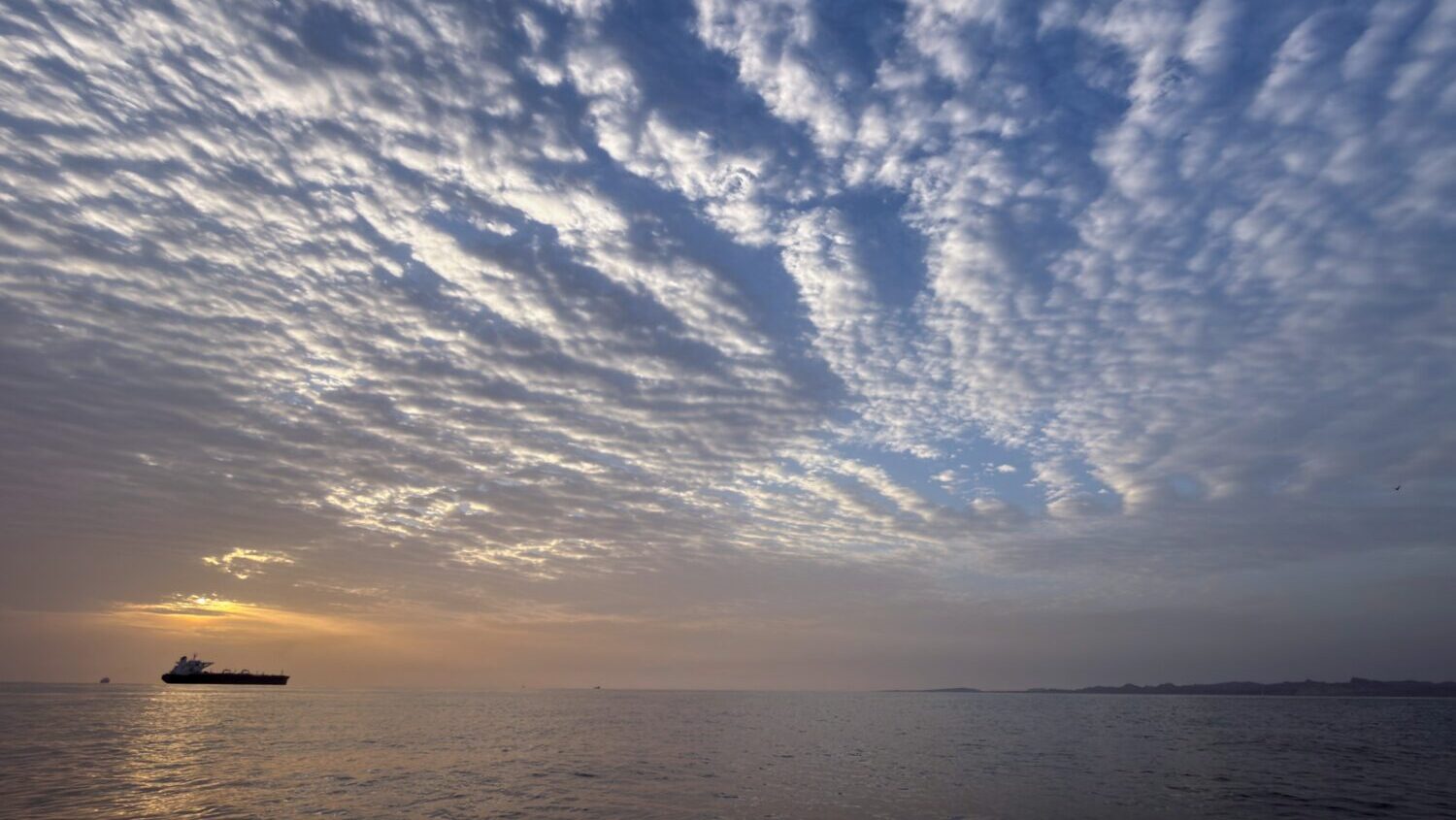 The sun rises behind a tanker anchored in the Strait of Hormuz off the coast of Qeshm Island, Iran,...