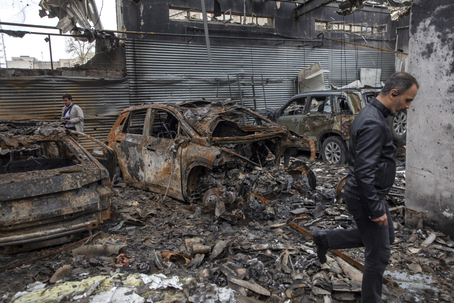 TEHRAN, IRAN - MARCH 28: People walk through the rubble of a foreign car repair workshop that was d...