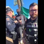 Sgt. Dusten Mullen, armed and wearing a face covering, stands near Hamilton High School students during an anti-ICE walkout protest in Chandler on Jan. 29, 2026. (Courtesy @turbo_rep on TikTok)