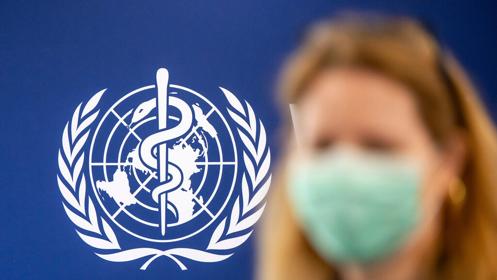 A person is wearing a protective face mask in front of the WHO logo, during the media regarding the...