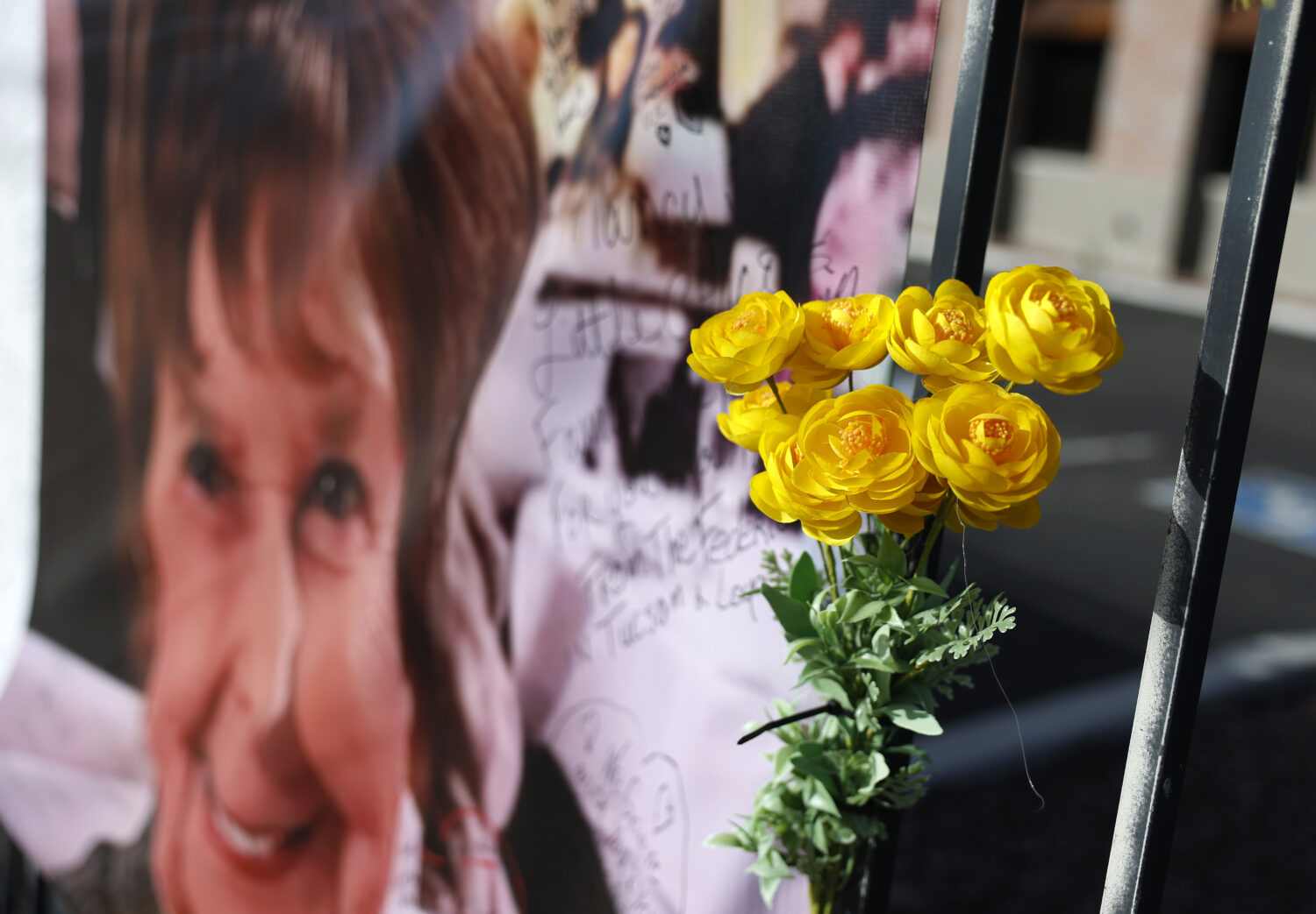 TUCSON, ARIZONA - MARCH 01: Yellow flowers hang from a photograph of Nancy Guthrie that is displaye...