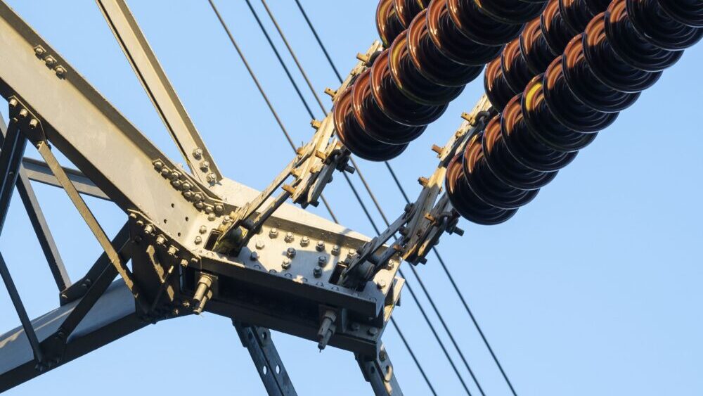 APS rate hike: Close-up of high voltage insulators on an electricity pylon. (Photo by: Planet One I...