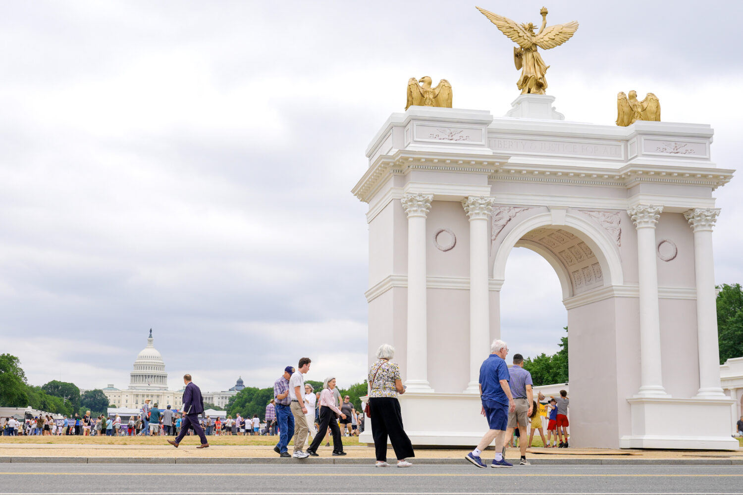 Visitors walk at the Great American State Fair with the triumphal arch model and the U.S. Capitol, ...