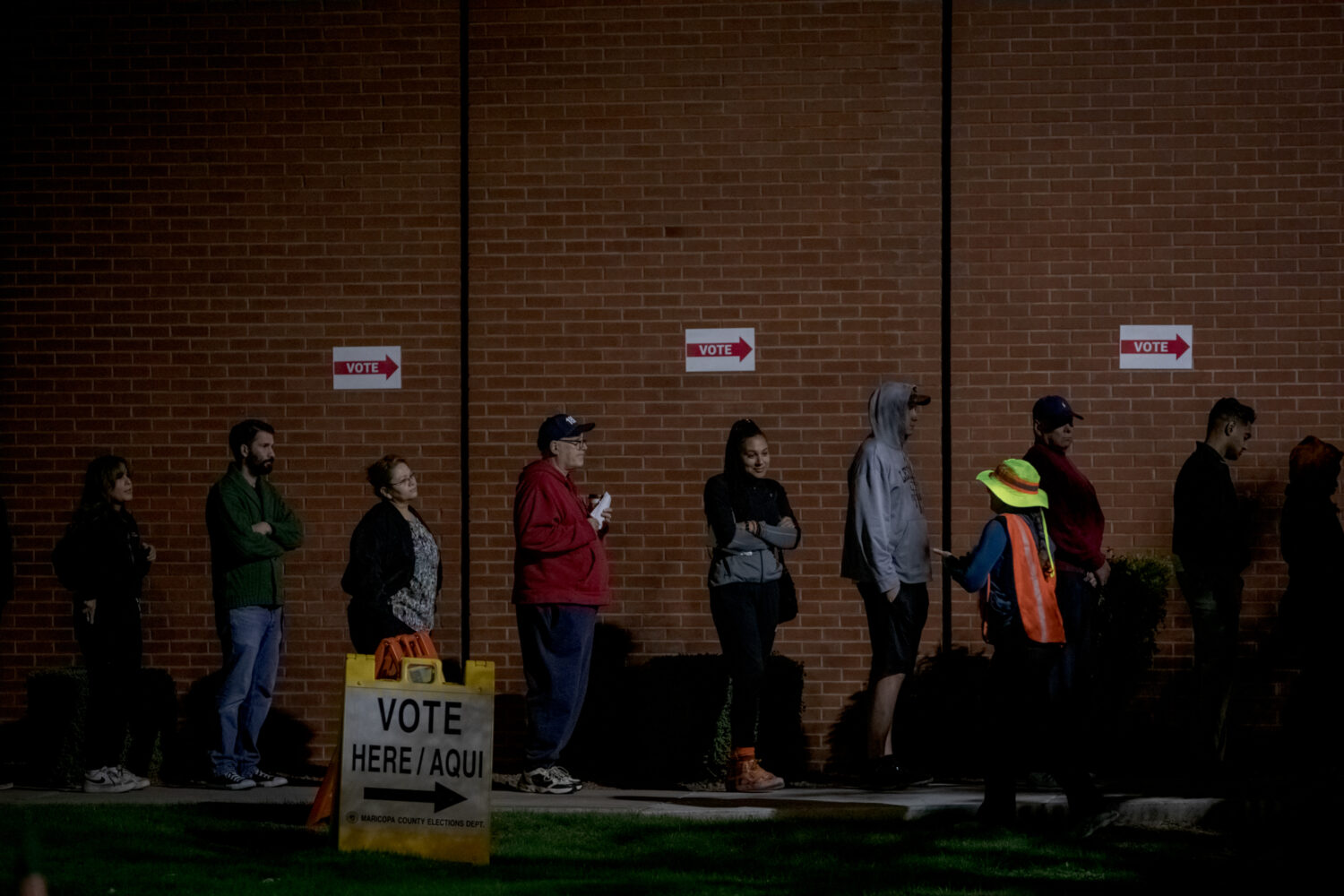 PHOENIX, AZ NOVEMBER 5: A poll worker tells voters that the polls are open while they wait in line ...