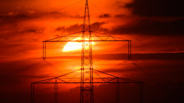A high-voltage pylon towers against the sunset sky in Brandenburg, Germany. APS customers shattered the utility's all-time electricity demand record as extreme heat pushed air conditioning use across Arizona to 9,053 megawatts. (Patrick Pleul/picture alliance via Getty Images)