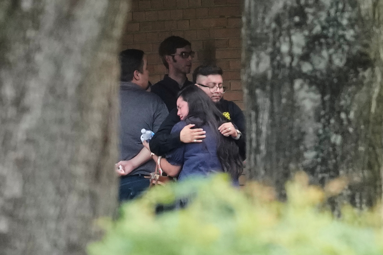 People hug outside the chapel during a public visitation for Lorenzo Salgado Araujo, who was shot a...