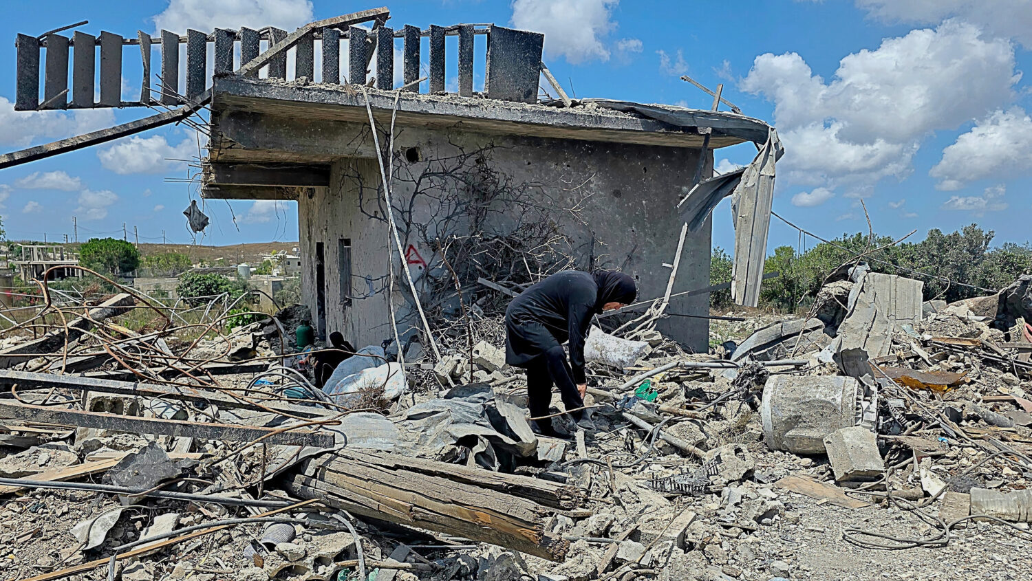 A Lebanese woman clears debris of her destroyed house in the village of Zawtar al-Gharbiyeh, southe...
