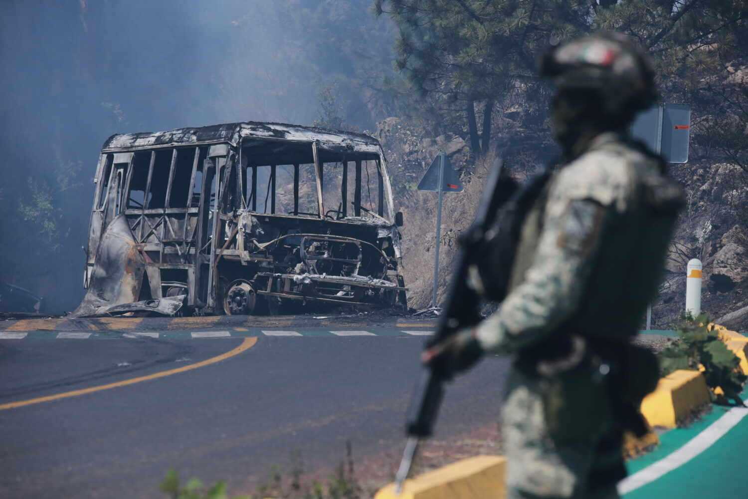 FILE - A soldier stands guard by a charred vehicle after it was set on fire in Cointzio, Michoacán...