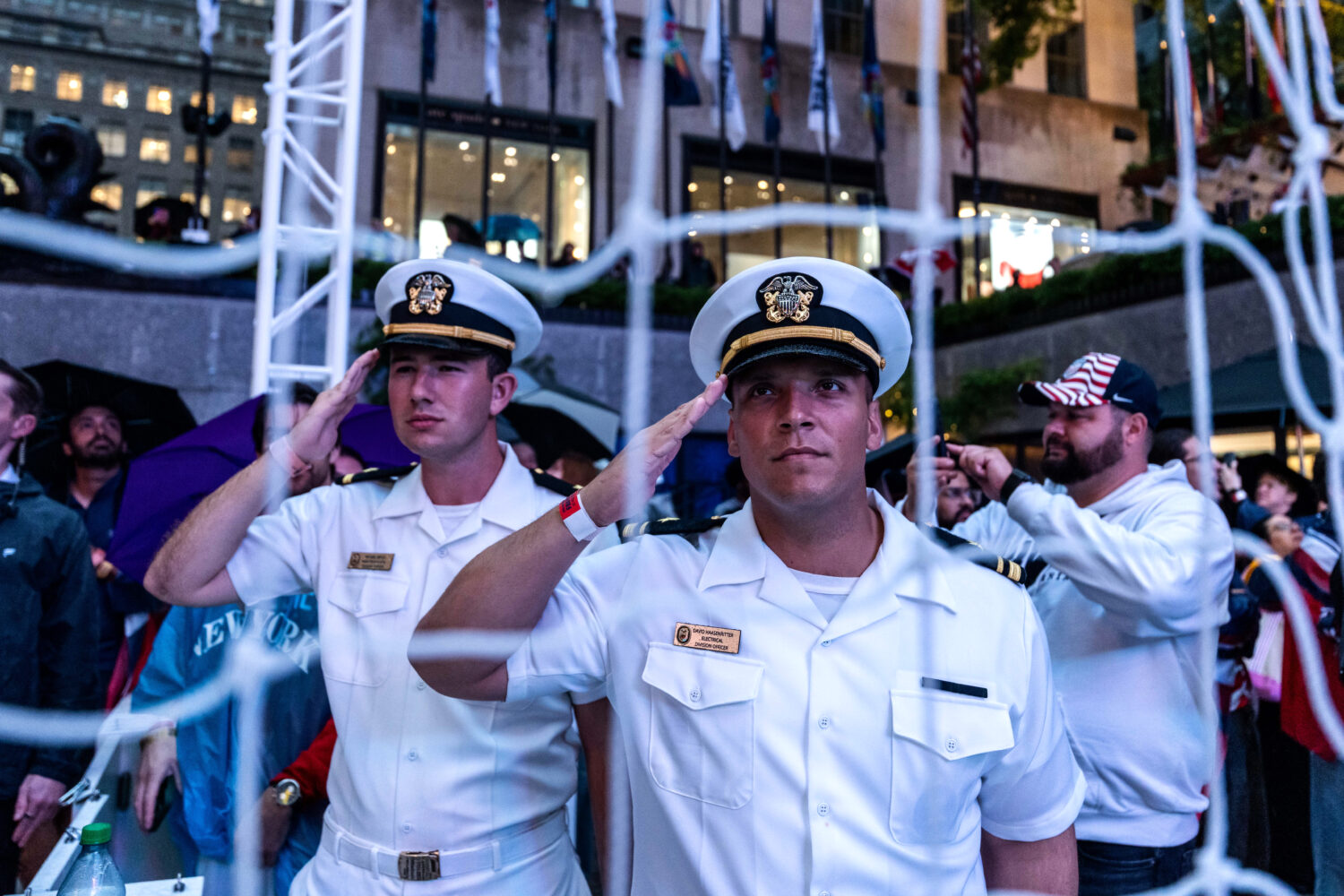 United States Navy personnel salute during the national anthem at a watch party in a fan village in...