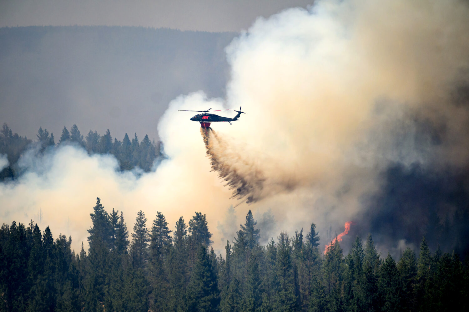 A helicopter drops water on the Akawa Butte fire on Friday, July 24, 2026, near Sisters, Ore. (AP P...