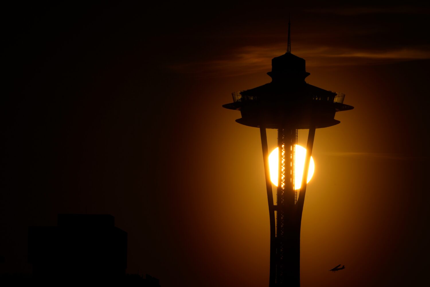 FILE - The sun sets behind the Space Needle as a small plane flies by on the first day of spring, T...