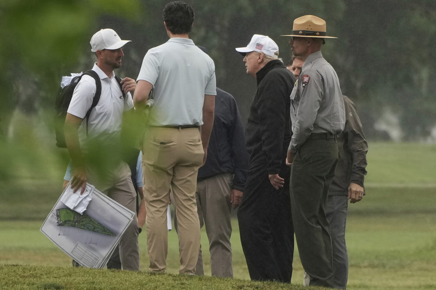 President Donald Trump, second right, tours the East Potomac Park golf course alongside a person ca...