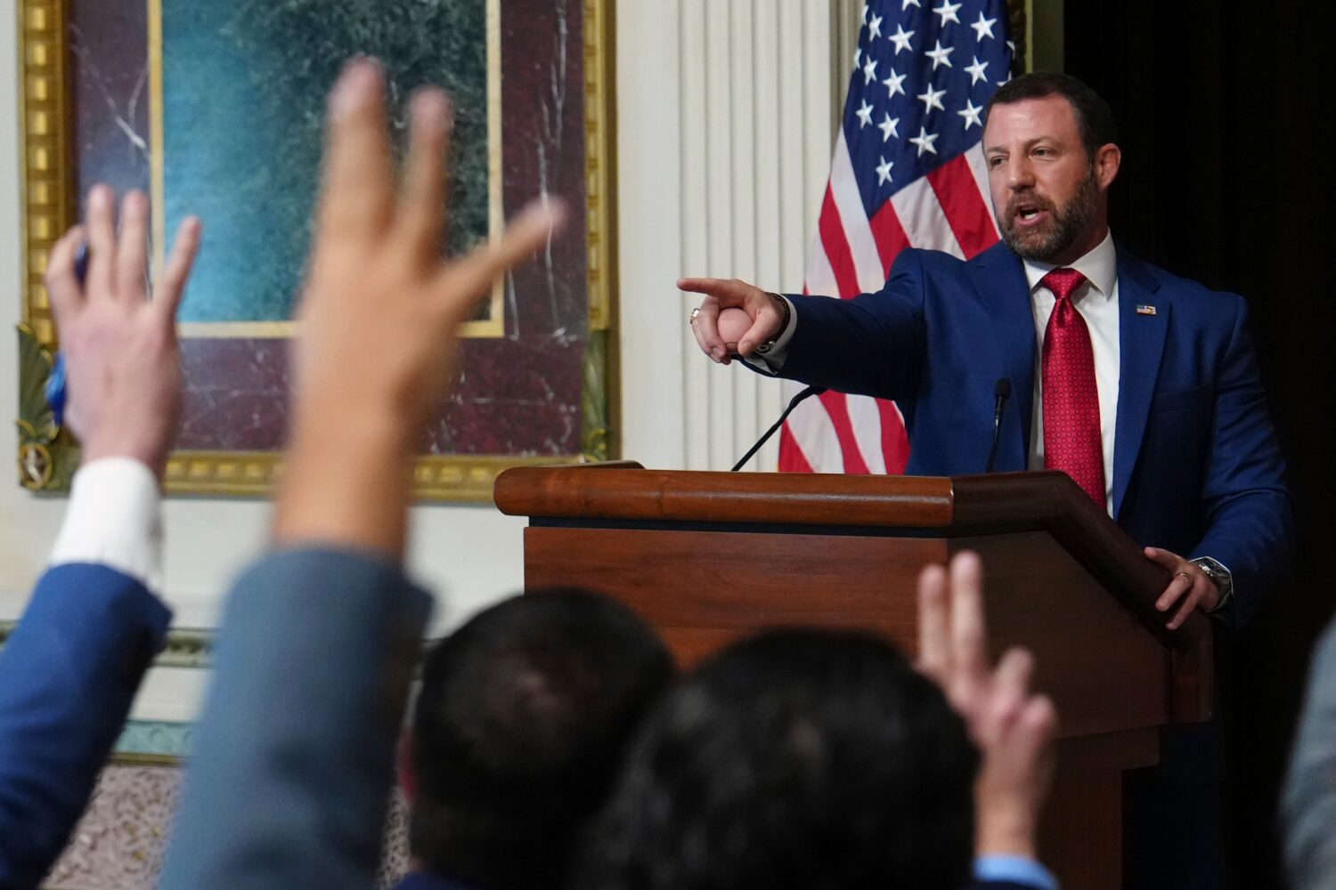 Reporters raise their hands as Homeland Security Secretary Markwayne Mullin speaks in the Indian Tr...