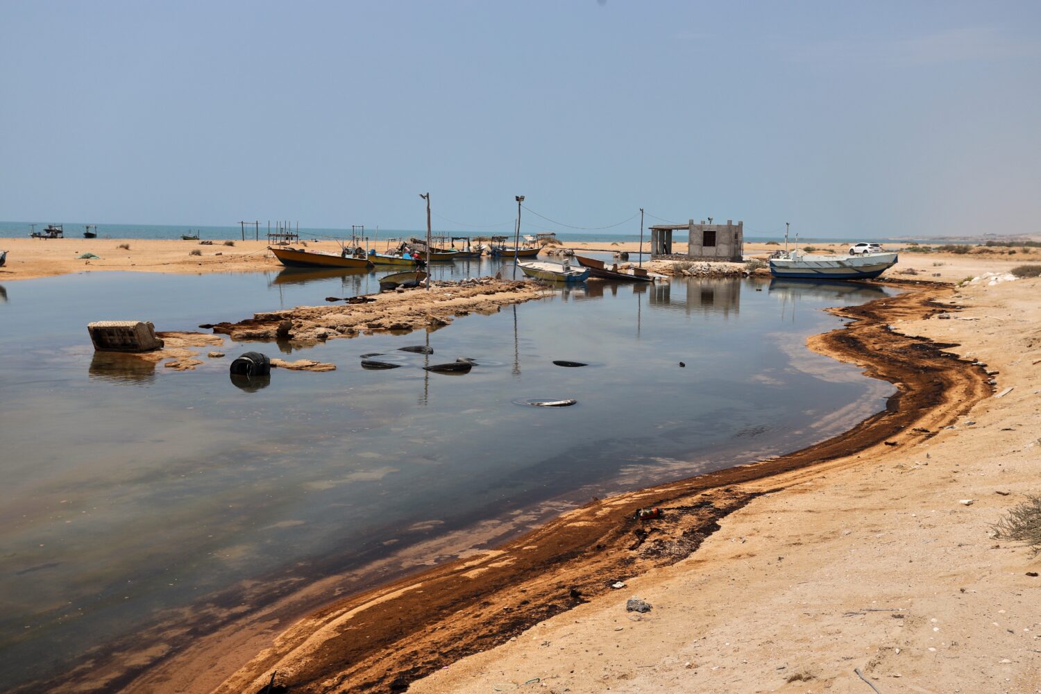 Oil residue lines the shore near fishing boats on Qeshm Island, Iran, Thursday, Aug. 13, 2026, amid...